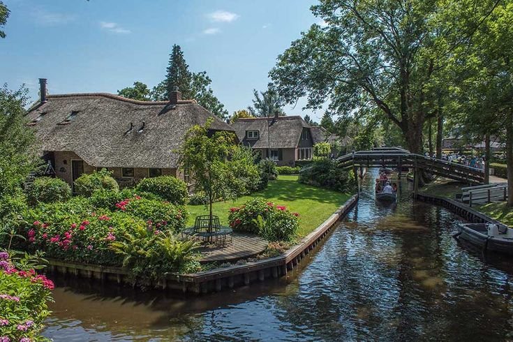 A wooden bridge and thatched farmhouse along a Giethoorn canal