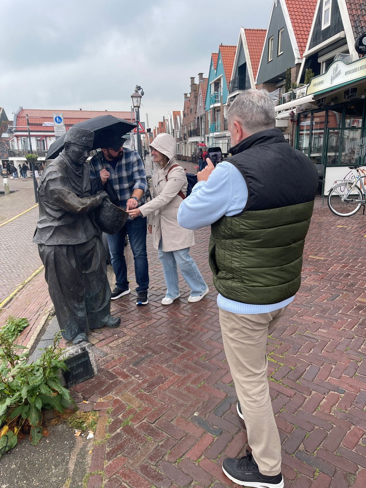 Mike taking a photo of guests with the fisherman statue in Volendam